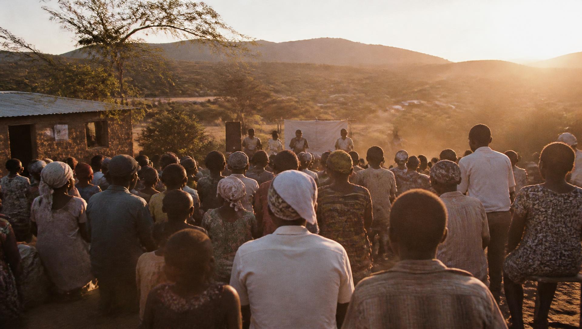 A community gathered outdoors at golden hour in a rural setting